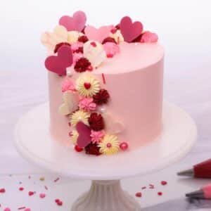 Pink birthday cake decorated with hearts and flowers